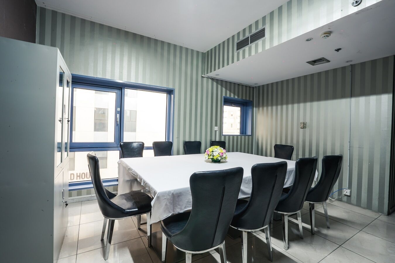 A conference room with a white table, black chairs, and striped wallpaper.