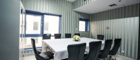 A conference room with a white table, black chairs, and striped wallpaper.