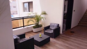 A balcony with wicker furniture, a potted plant, and a staircase. - 3-room apartment near the center. Air-conditioned and free WLan (Lomé)