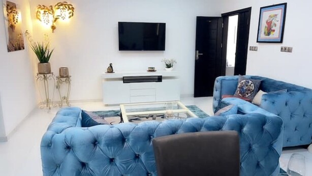 A living room with a blue sofa, a coffee table, a flat-screen TV, and a white cabinet. - 3-room apartment near the center. Air-conditioned and free WLan (Lomé)
