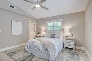 A bedroom with a bed, nightstands, a ceiling fan, a window, and a framed picture on the wall.
