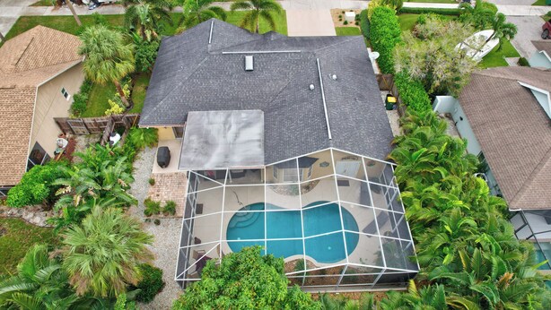 A residential property with a swimming pool, surrounded by lush greenery and a well-maintained lawn. - Centrally Located Pool Home in Naples (Naples)