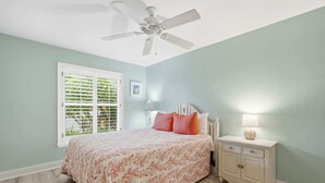 A bedroom with a bed, a nightstand, a ceiling fan, and a window with shutters. - Centrally Located Pool Home in Naples (Naples)