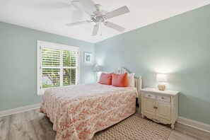 A bedroom with a bed, a nightstand, a ceiling fan, and a window with shutters. - Centrally Located Pool Home in Naples (Naples)