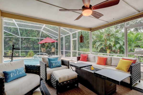A sunroom with a pool, seating area, and large windows.