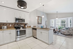 A modern kitchen with white cabinetry, stainless steel appliances, and a central island.
