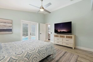 A bedroom with a bed, a ceiling fan, a television on a dresser, and a door leading to a balcony. - Centrally Located Pool Home in Naples (Naples)