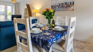 A dining area with a table set for four, a vase of flowers, and a painting on the wall. - Stones Throw by Interhome (Charlestown)
