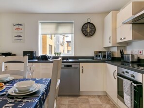 Una cocina moderna con lavavajillas, microondas y horno. Se ve una ventana con vistas a edificios.