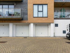 A modern building with a brick facade, large windows, and a covered outdoor area with a car parked nearby. - Stones Throw by Interhome (Charlestown)