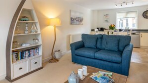 A living room with a blue sofa, a bookshelf, a lamp, and a coffee table. - Stones Throw by Interhome (Charlestown)