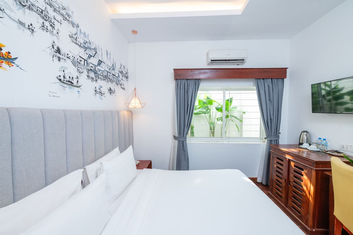 Une chambre d’hôtel avec un lit, un bureau, une télévision et une fenêtre avec des rideaux.
