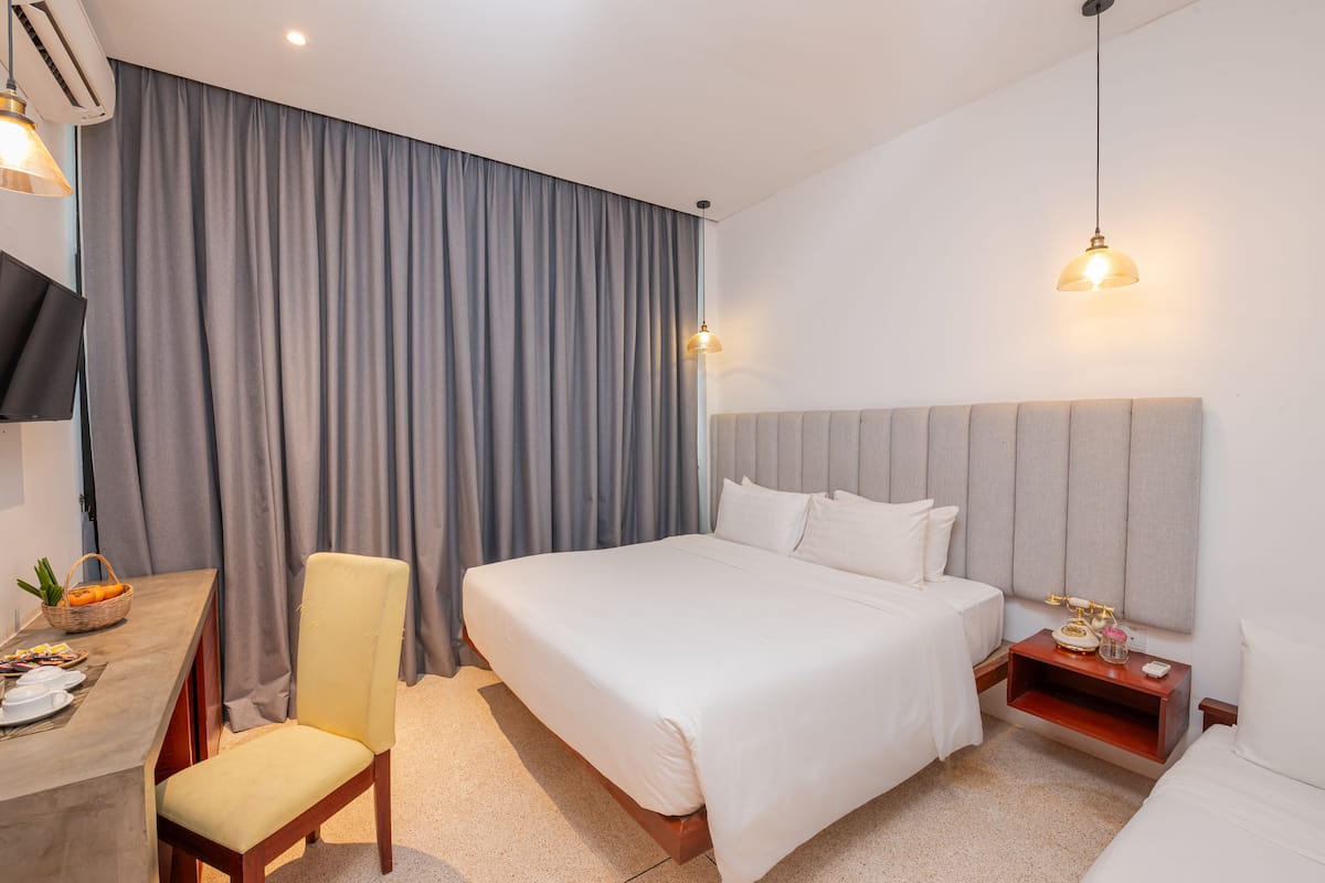 Une chambre d’hôtel avec un grand lit, un bureau avec une chaise, une télévision et une table de chevet avec une lampe.