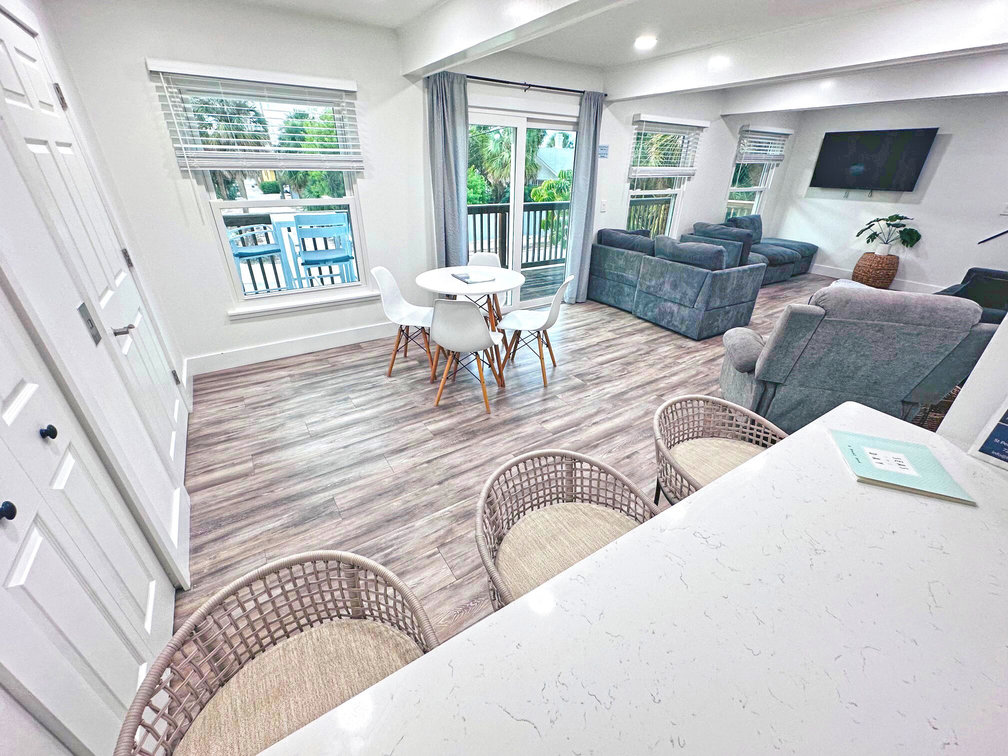 A modern living room with a dining area, large windows, and a flat-screen TV.