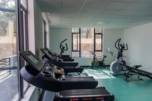 Un gimnasio con cintas de correr, bicicletas estáticas y equipamiento de ejercicio.