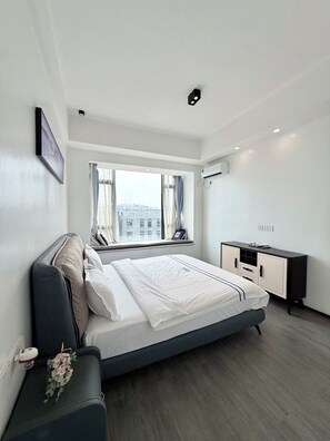 A modern bedroom with a large bed, a bedside table, a dresser, and a window with curtains. - Elizabeth Golf Apartment (Kigali)