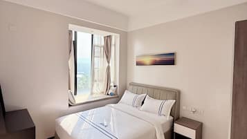 Una habitación de hotel moderna con una cama grande, un escritorio y un ventanal con cortinas.