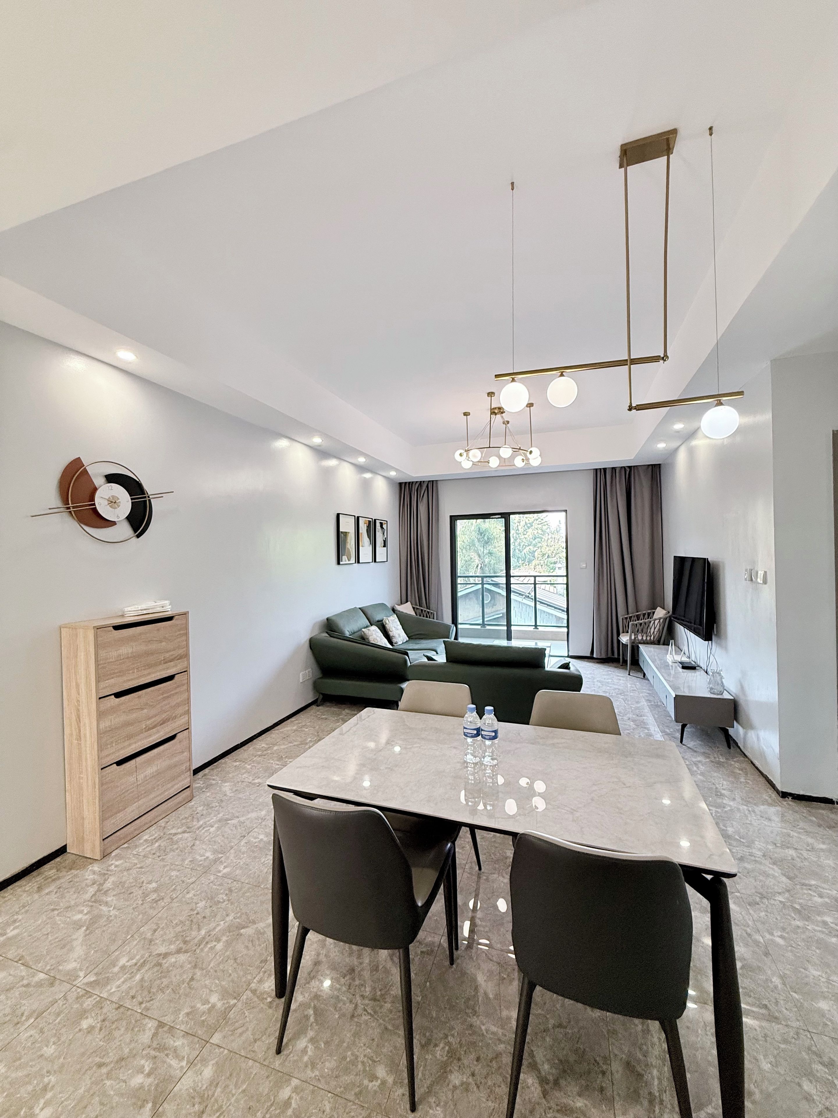 A modern living room with a dining area, a sofa, a TV, and a wooden cabinet.