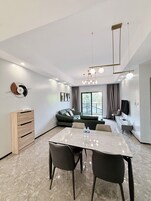 Un salon moderne comprenant un coin repas, un canapé, un téléviseur et un meuble en bois.