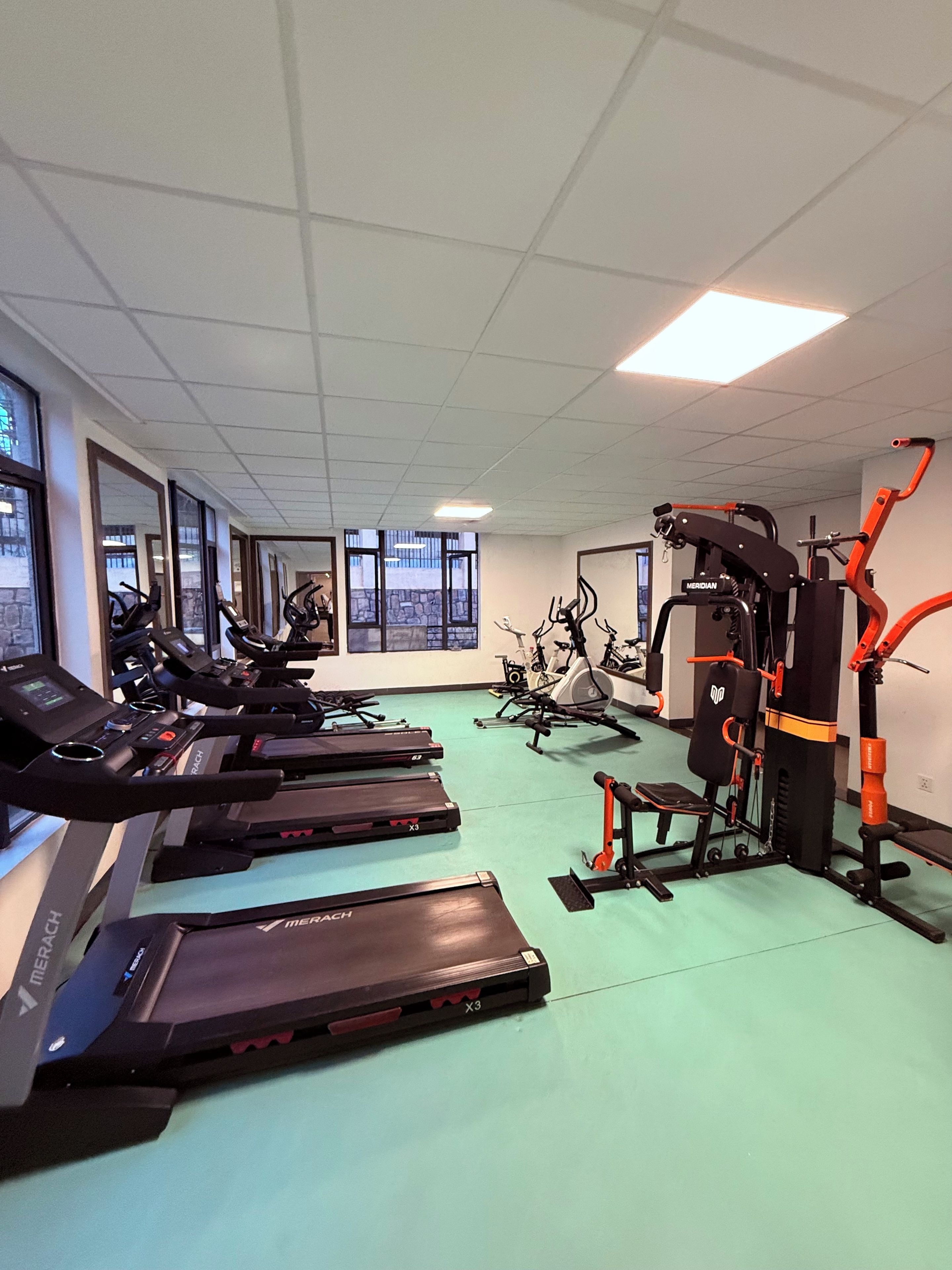 Un gimnasio con cintas de correr, bicicletas estáticas y máquinas de pesas.