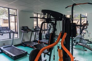 Un gimnasio con cintas de correr, máquinas de pesas y equipo de ejercicio.