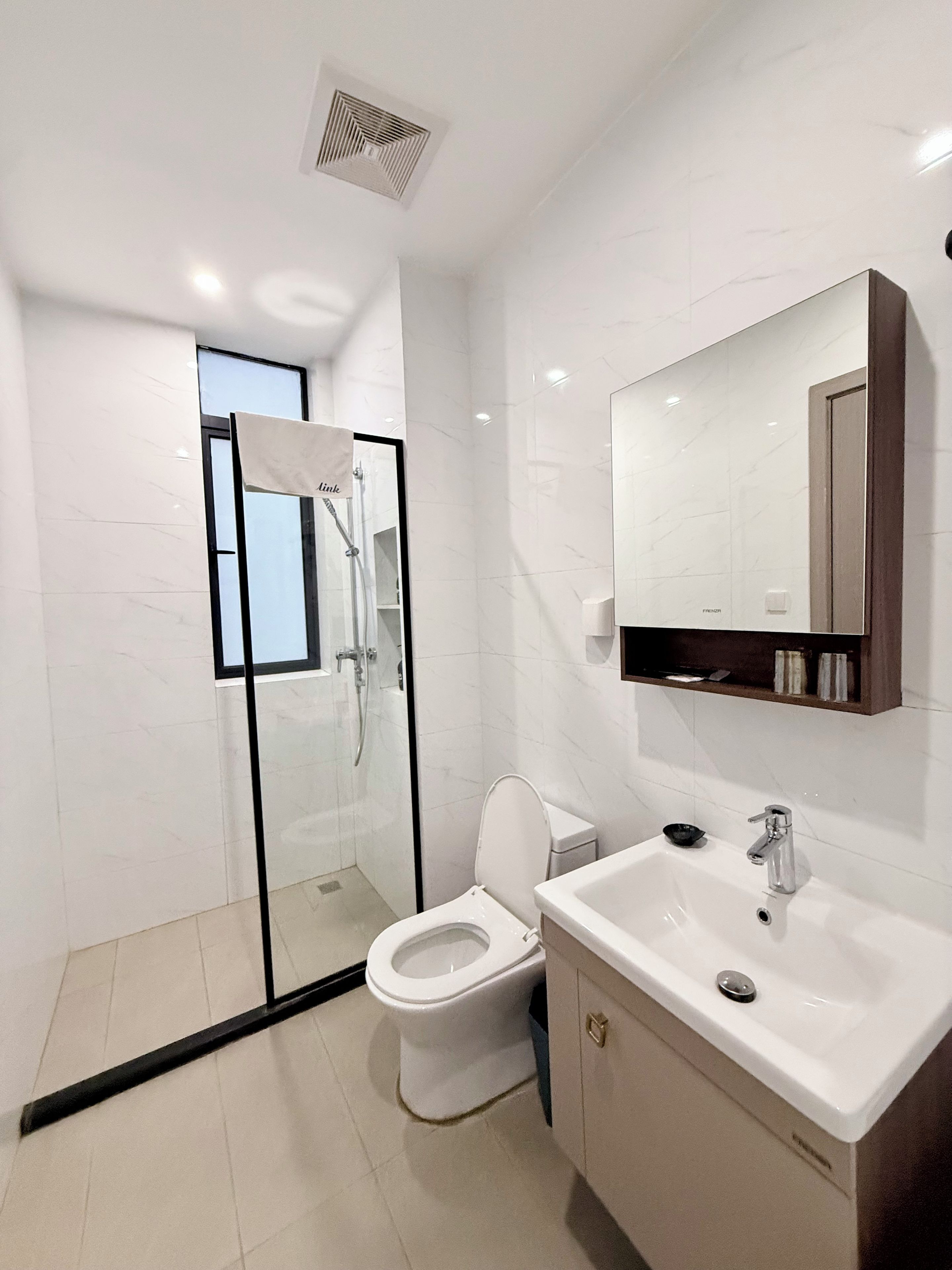 A modern bathroom with a glass-enclosed shower, a toilet, a sink, and a mirror.