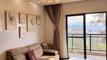 Ein modernes Wohnzimmer mit einer Couch, einem Couchtisch und einem großen Fenster mit Blick auf die Stadtlandschaft.
