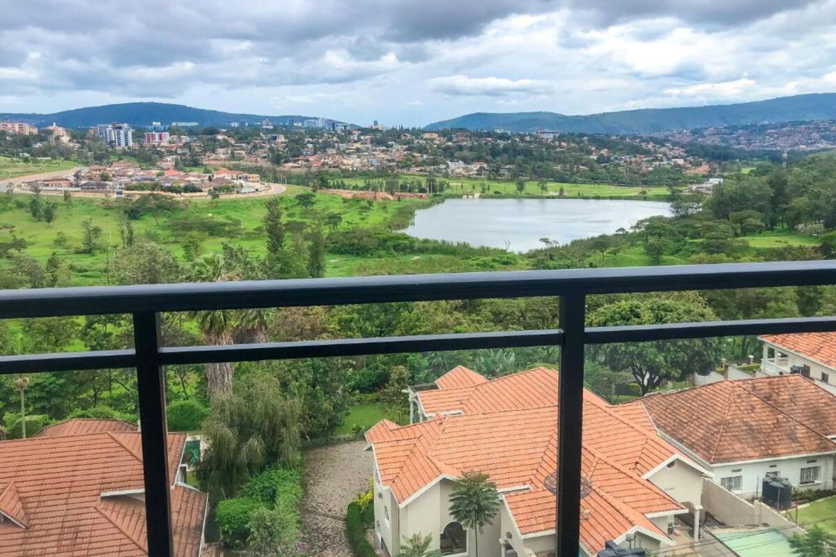 A view of a residential area with houses, a lake, and surrounding greenery.