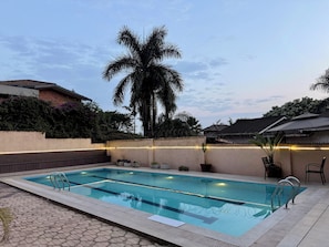 A rectangular swimming pool with a clear blue waterline, surrounded by a tiled deck. - Elizabeth Golf Apartment (Kigali)