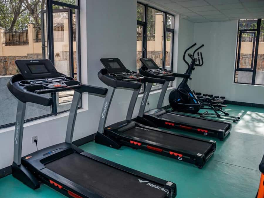 Un gimnasio con cintas de correr, bicicletas estáticas y una máquina de remo.