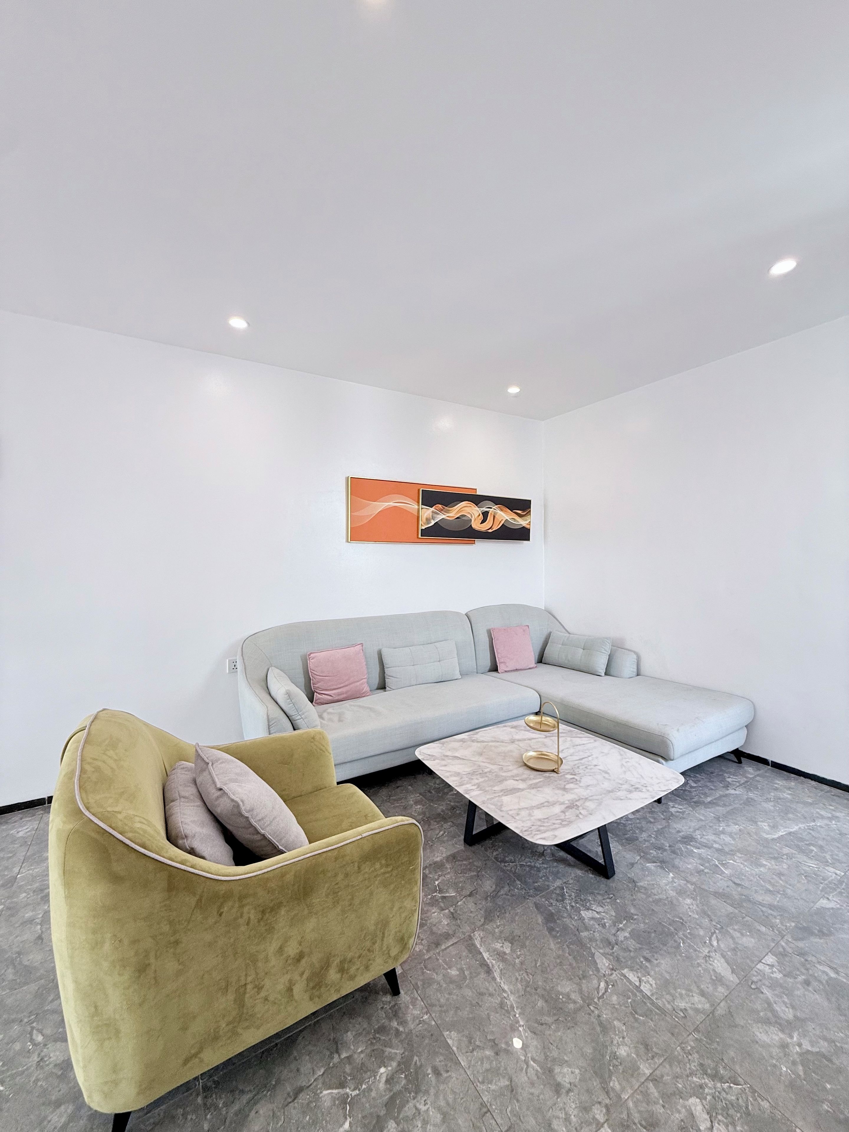 Una sala moderna con un sofá, un sillón y una mesa de centro de mármol.
