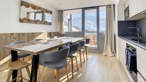 Eine moderne Küche mit großem Fenster, Holzboden und Essbereich mit langem Tisch und Stühlen.