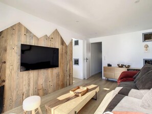 A modern living room with a wooden accent wall, a flat-screen TV, a wooden coffee table, a sofa, and a minimalist sideboard.
