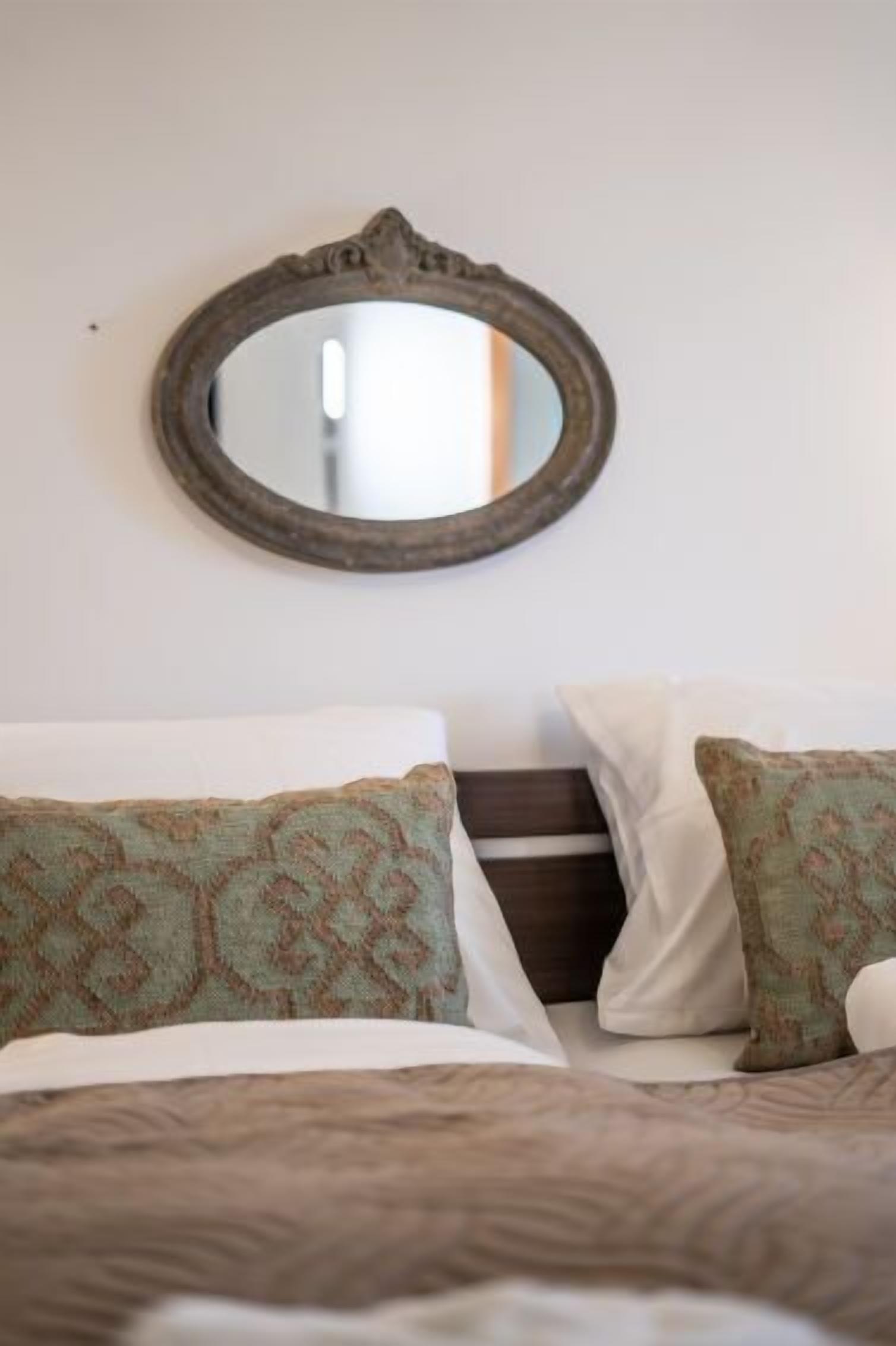 A bed with patterned pillows and a plain wall.