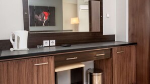 A modern bathroom with a dark wood vanity, a mirror, a white kettle, and a small trash bin. - Sinada Otel (Eskisehir)