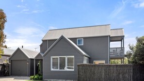 Ein zweistöckiges Haus mit grauem Anstrich, einer Garage vorne und einem kleinen Balkon im oberen Geschoss.