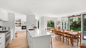 A modern kitchen with white cabinetry, a central island, and a dining area with wooden furniture.