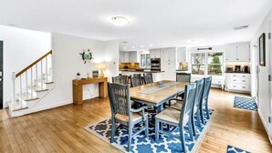 A spacious kitchen with white cabinets, a wooden dining table, and blue chairs.