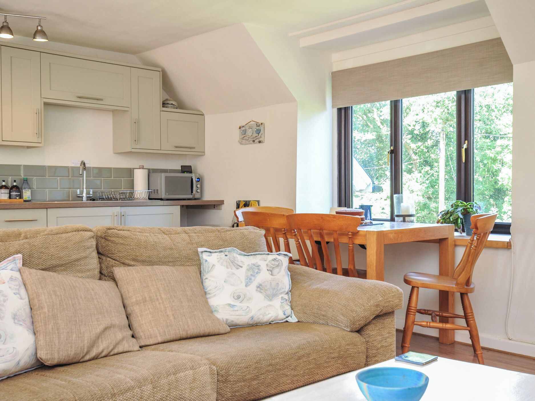 A cozy living room with a sofa, a dining table, and a kitchen area with cabinets and appliances.
