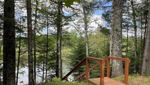 A wooden deck with a metal railing overlooking a forested area and a body of water. - Tree Top Retreat on the Peaceful Flambeau River! (Park Falls)