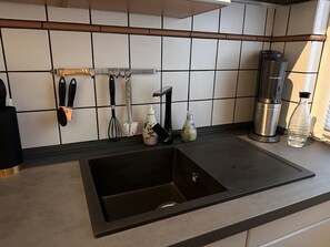 A kitchen with a stainless steel sink, a coffee maker, and a bottle of hand soap on the counter. - Vacation apartment in Wuppertal (Wuppertal)