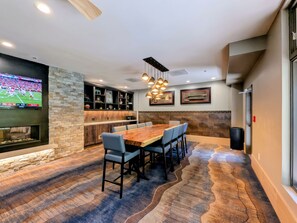 A modern kitchen with a stone backsplash, a bar area, and a dining space with a large wooden table and chairs. - Walk to Dining, Shops, Gondola! Great Hot Tubs! (Keystone)