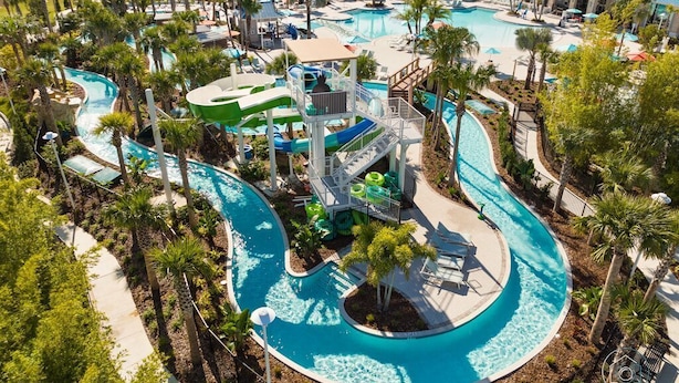 Vue aérienne d’un complexe hôtelier doté de plusieurs piscines, de toboggans aquatiques et de palmiers.