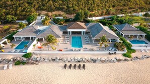 Un resort con varias piscinas, una zona de playa y montañas al fondo.