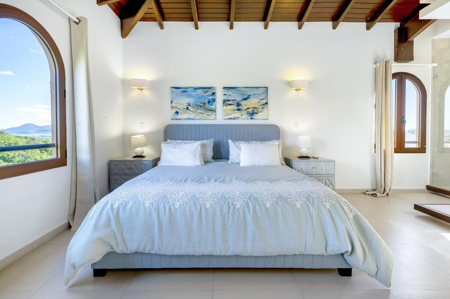 Une chambre à coucher avec un grand lit, deux lampes fixées au mur et deux tableaux.