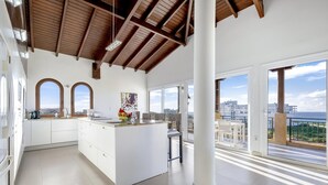 Una cocina moderna con una isla central, ventanas amplias y vista al mar.