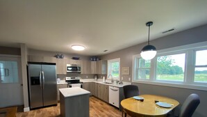 A modern kitchen with a central island, stainless steel appliances, and a dining area with a round table and chairs.