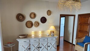 Ein Wohnzimmer mit einem weißen Schrank, einem Korbstuhl und einer Chandelüster.