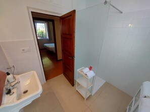 A bathroom with a sink, a shower, and a small shelf with towels. - Magnificent wooded villa, ideally located close to the beach. (L'Escala)