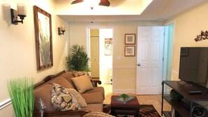 A living room with a sofa, a coffee table, a TV stand, and a door leading to another room. - 2 Bedroom Apt Overlooking Dunedin Town Square (Dunedin)
